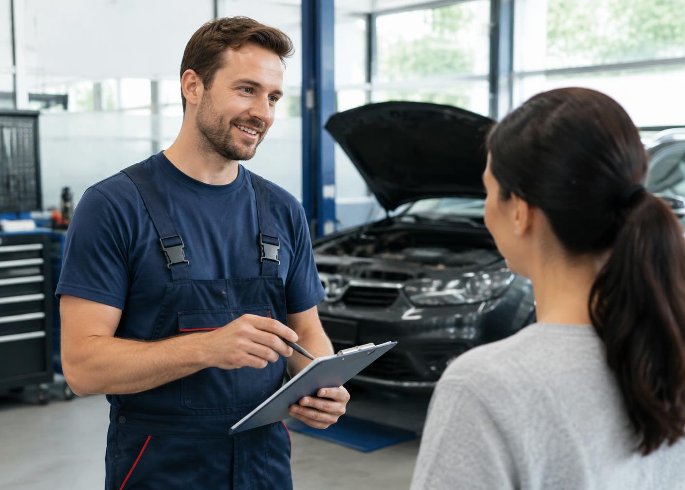 Mechaniker berät eine Kundin über den geplanten Fahrzeugservice